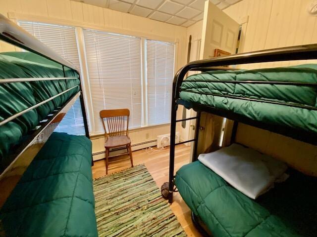 bedroom with baseboard heating, a paneled ceiling, and hardwood / wood-style floors