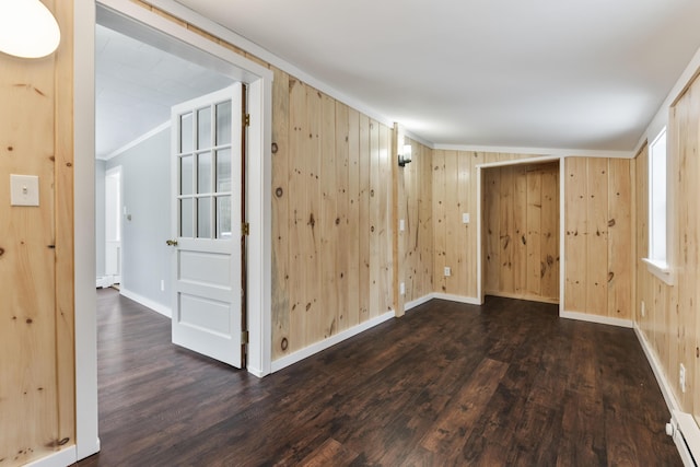 spare room with crown molding, a baseboard radiator, dark hardwood / wood-style floors, and wood walls