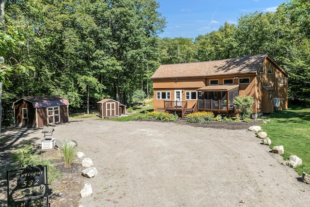 rear view of house with a wooden deck and a storage unit