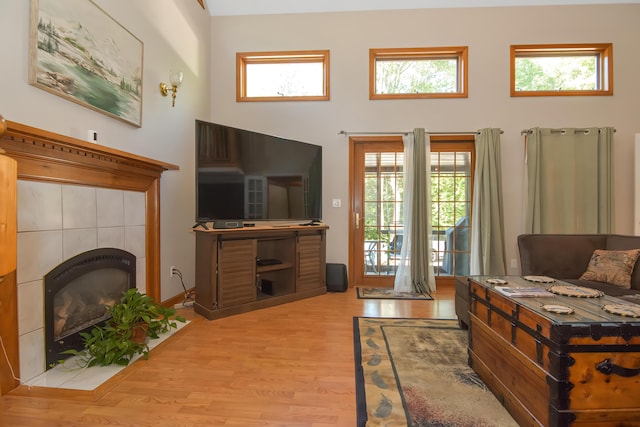 bedroom featuring a tiled fireplace, access to outside, and light wood-type flooring