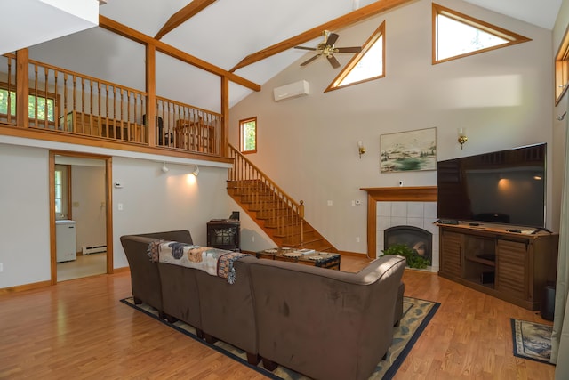 living room with a tile fireplace, a healthy amount of sunlight, baseboard heating, and light hardwood / wood-style floors