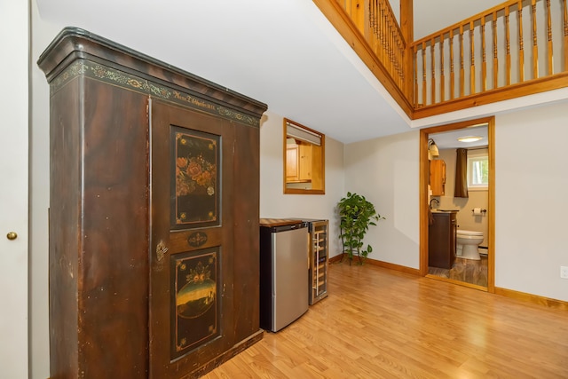 corridor with beverage cooler and light hardwood / wood-style flooring