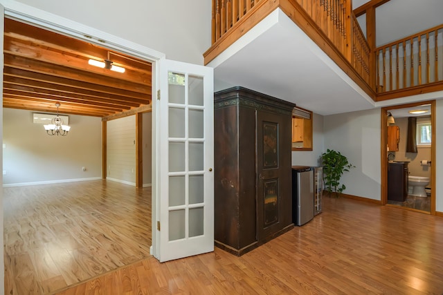 interior space featuring a high ceiling, a notable chandelier, light hardwood / wood-style floors, and beam ceiling