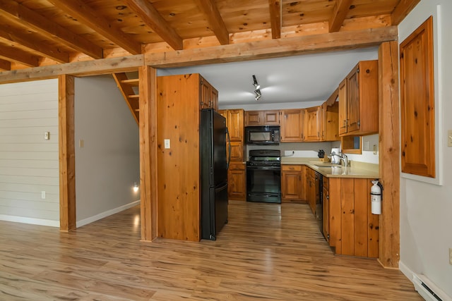 kitchen featuring baseboard heating, beamed ceiling, light wood-type flooring, and black appliances