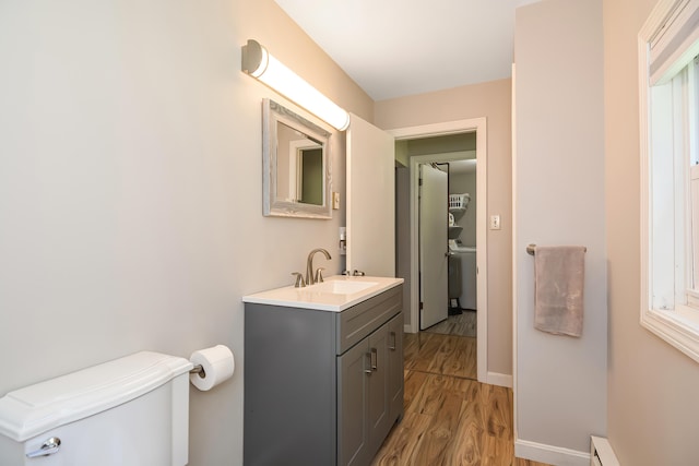 bathroom featuring vanity, wood-type flooring, baseboard heating, and toilet