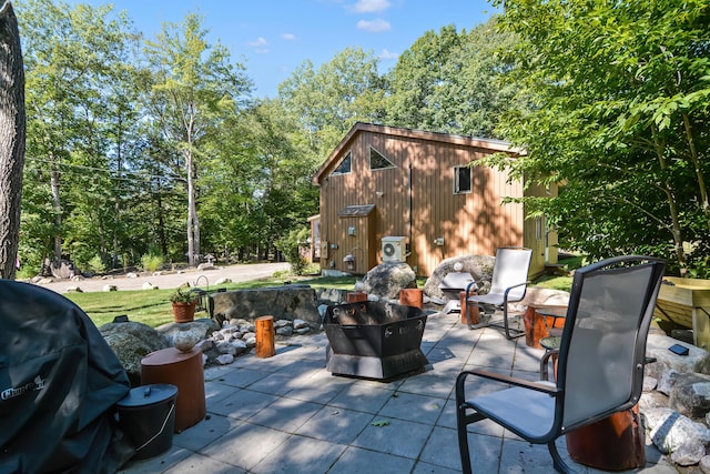 view of patio featuring an outbuilding, a grill, and a fire pit