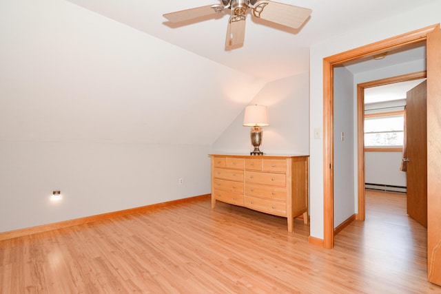 unfurnished bedroom featuring baseboard heating, ceiling fan, vaulted ceiling, and light hardwood / wood-style floors