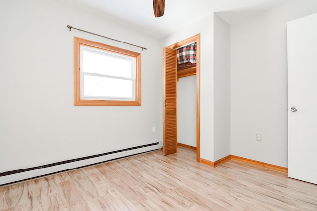 unfurnished bedroom featuring a baseboard heating unit, a closet, ceiling fan, and light wood-type flooring