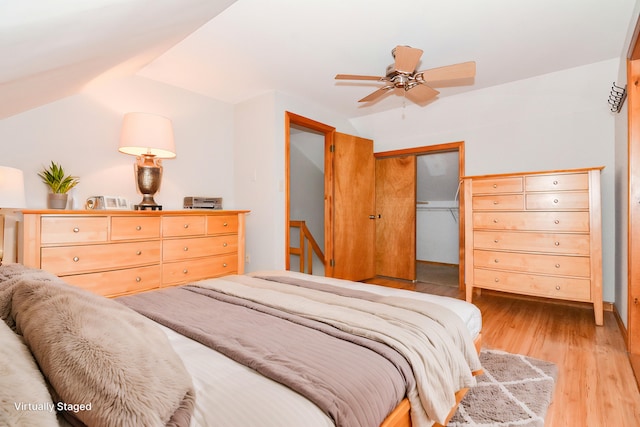 bedroom featuring lofted ceiling, light hardwood / wood-style floors, a closet, and ceiling fan