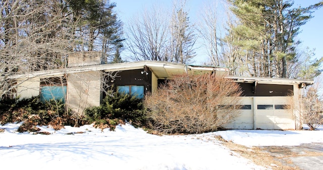 snow covered property with a garage