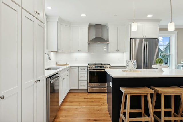 kitchen with appliances with stainless steel finishes, sink, white cabinets, backsplash, and wall chimney range hood