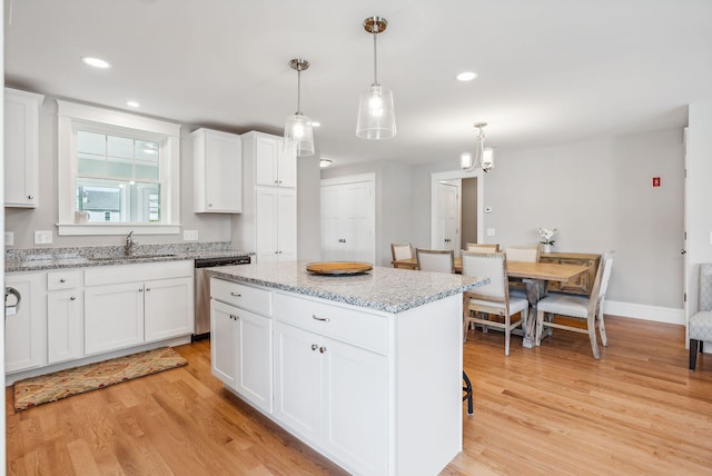 kitchen with sink, decorative light fixtures, a center island, stainless steel dishwasher, and white cabinets