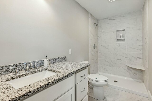 bathroom featuring vanity, toilet, and tiled shower