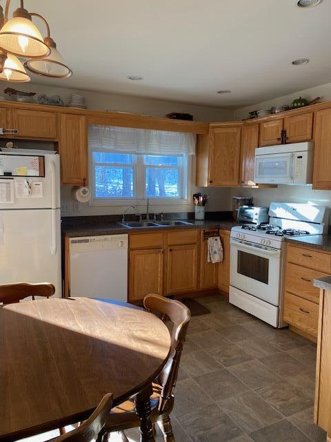 kitchen with white appliances, decorative light fixtures, and sink