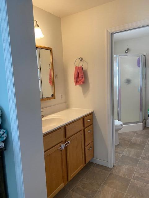 bathroom featuring vanity, a shower with shower door, and toilet