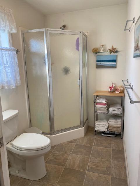 bathroom with a shower with door and toilet