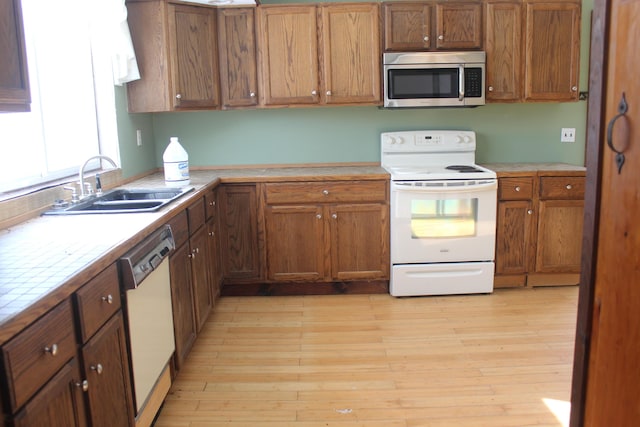 kitchen featuring tile counters, sink, white appliances, and light hardwood / wood-style flooring