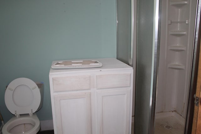 bathroom featuring vanity, a shower with shower door, and toilet