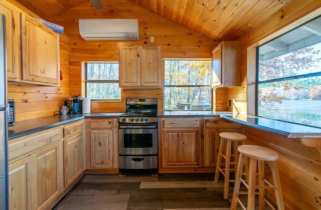 kitchen featuring dark wood-type flooring, a wall mounted AC, stainless steel stove, and wooden walls