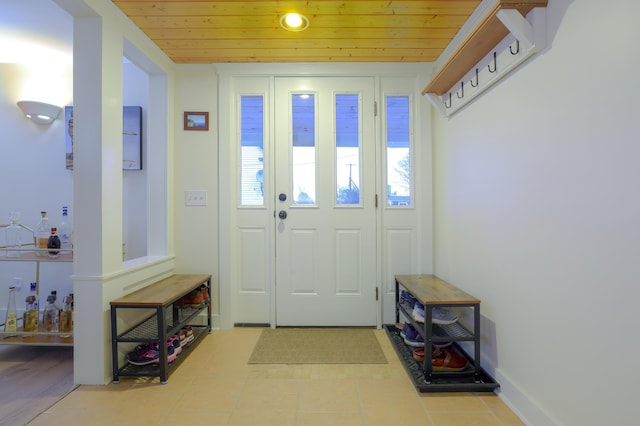 entryway with light tile patterned floors, wood ceiling, and a wealth of natural light