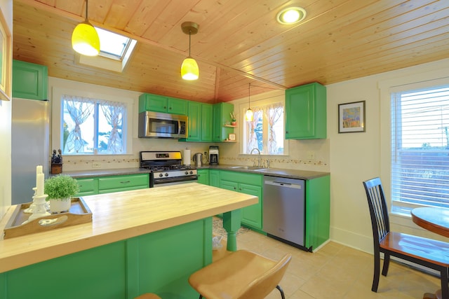 kitchen with butcher block counters, sink, appliances with stainless steel finishes, green cabinets, and pendant lighting