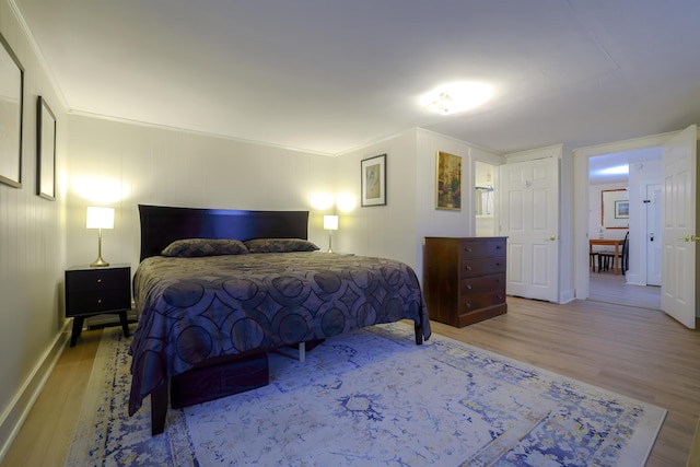 bedroom featuring crown molding and light hardwood / wood-style flooring