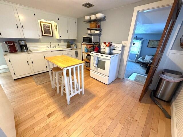 kitchen with white cabinetry, white range with electric cooktop, sink, and light hardwood / wood-style floors