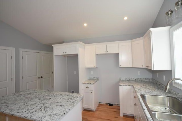 kitchen featuring light stone countertops, sink, a kitchen island, and white cabinets