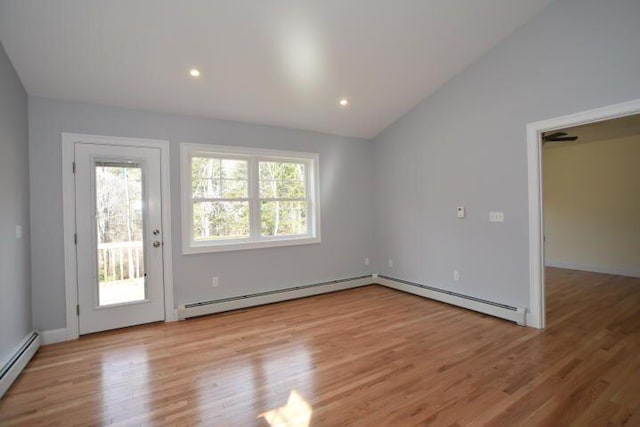 interior space with vaulted ceiling, a baseboard heating unit, and light hardwood / wood-style floors