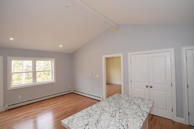 bedroom featuring lofted ceiling, light hardwood / wood-style floors, and a baseboard heating unit