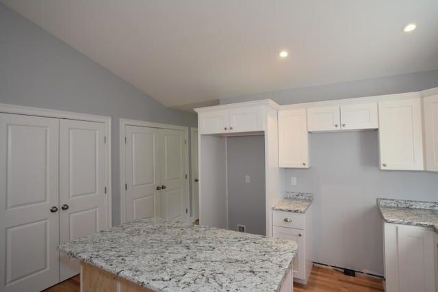 kitchen featuring light stone countertops, a center island, and white cabinets