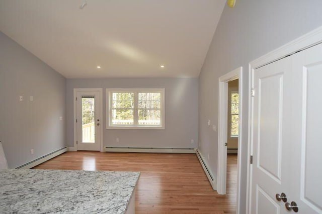 entryway featuring lofted ceiling, baseboard heating, and light hardwood / wood-style flooring