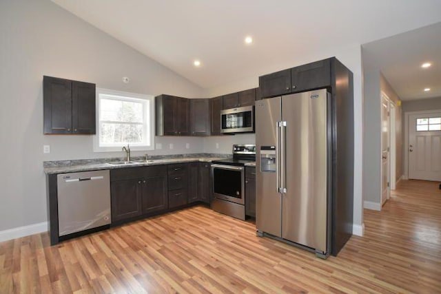 kitchen with sink, appliances with stainless steel finishes, light stone counters, dark brown cabinetry, and light hardwood / wood-style floors