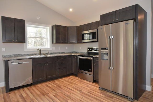 kitchen featuring vaulted ceiling, sink, dark brown cabinetry, stainless steel appliances, and light wood-type flooring