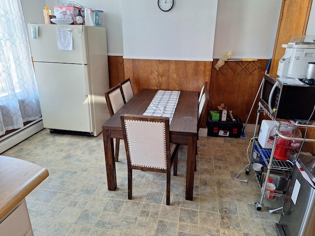 dining area featuring wooden walls and a baseboard heating unit