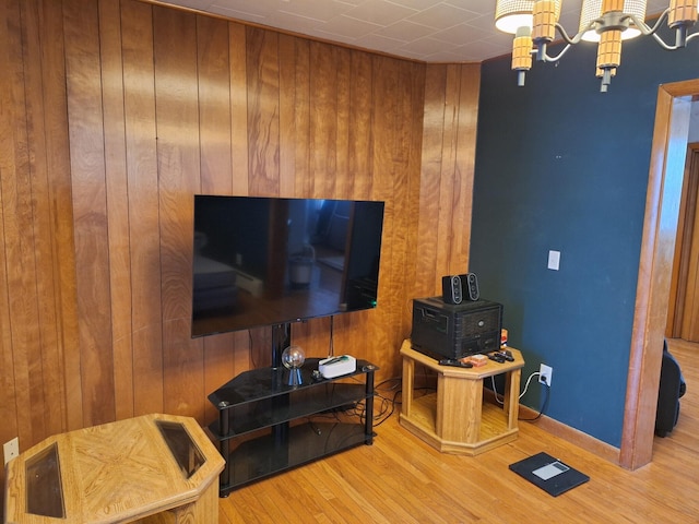 living room featuring wooden walls, light hardwood / wood-style floors, and a chandelier