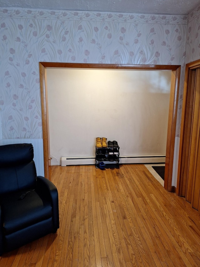 unfurnished room with hardwood / wood-style flooring, a baseboard radiator, and a textured ceiling