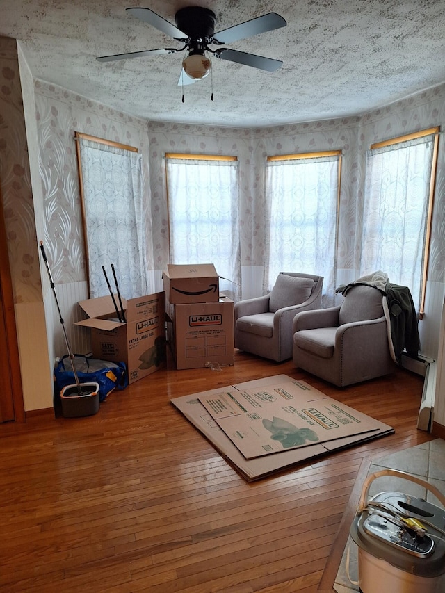 living room featuring hardwood / wood-style flooring, ceiling fan, and a textured ceiling