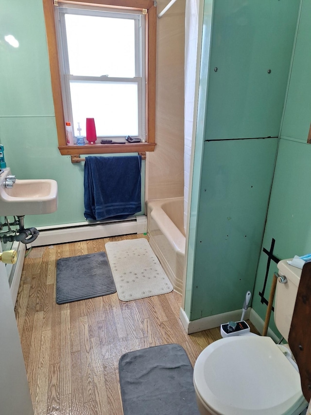 full bathroom featuring a baseboard heating unit, wood-type flooring, bathing tub / shower combination, and toilet