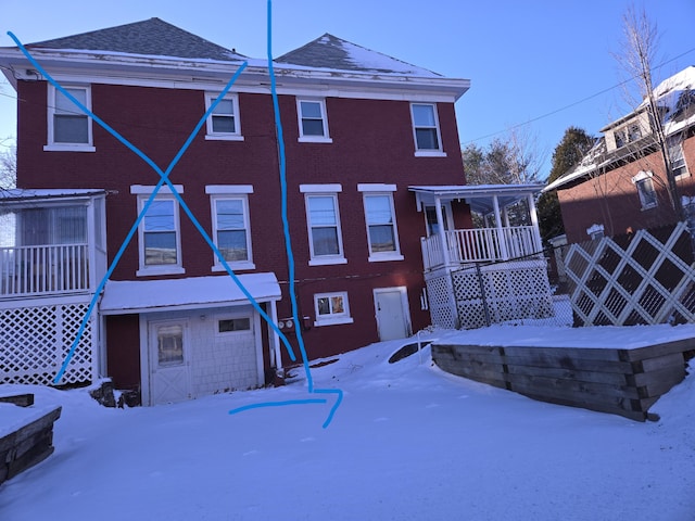 snow covered back of property with a garage