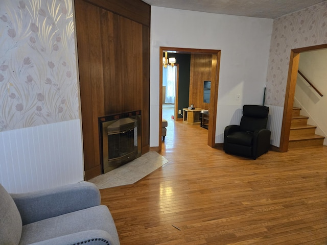 36 Erchles St, Rumford, ME 04276 - living room featuring light wood finished floors, a notable chandelier, wallpapered walls, a large fireplace, and stairs