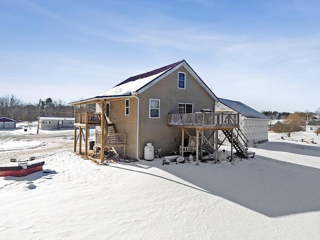 snow covered property with a deck and stairs