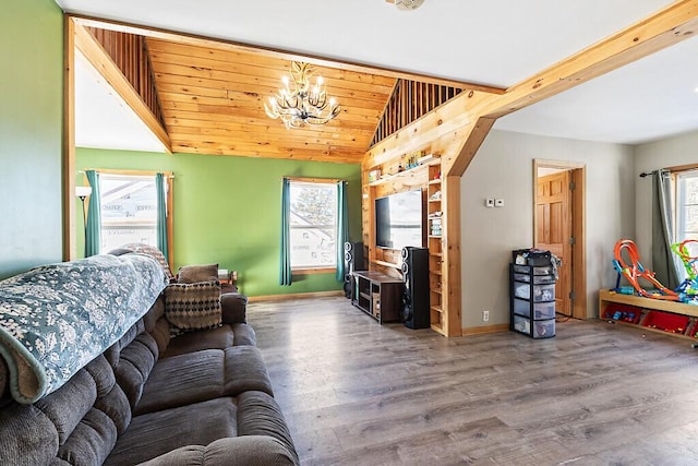 living room featuring a healthy amount of sunlight, wood-type flooring, vaulted ceiling, and a notable chandelier