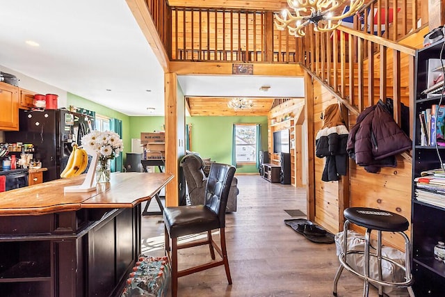 kitchen featuring hardwood / wood-style flooring, black fridge, and a notable chandelier