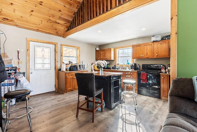 kitchen with a center island, black electric range oven, a breakfast bar area, and light wood-type flooring