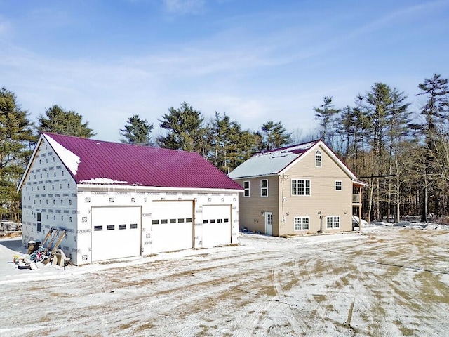 exterior space with a garage, an outbuilding, and metal roof