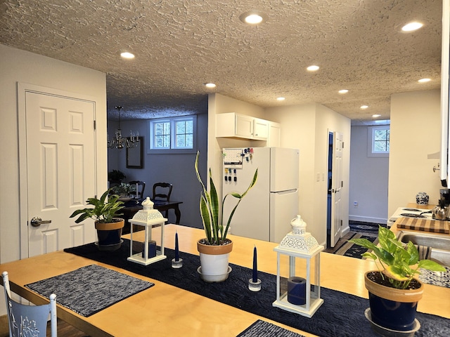 interior space with white fridge, white cabinets, and a textured ceiling