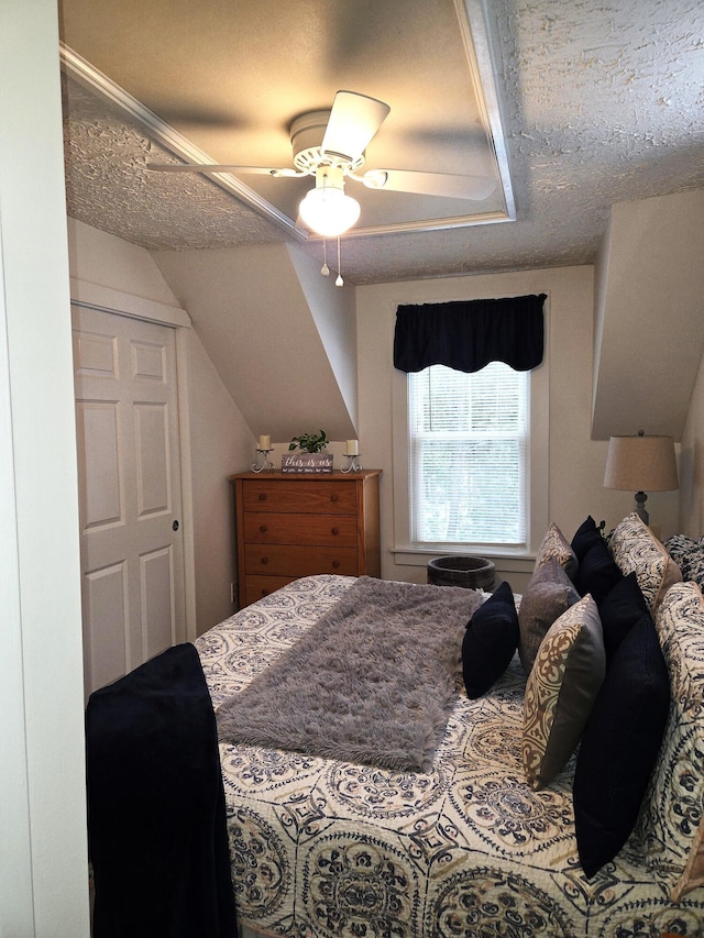 bedroom featuring vaulted ceiling, ceiling fan, and a textured ceiling