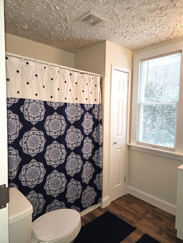 bathroom with hardwood / wood-style flooring, a textured ceiling, and toilet