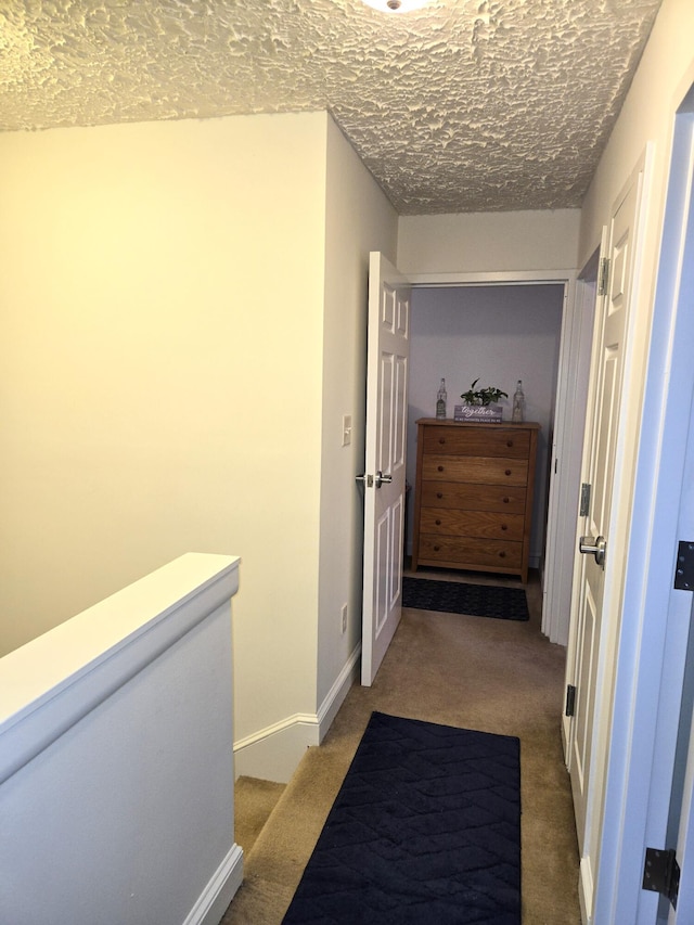 hall with carpet flooring and a textured ceiling